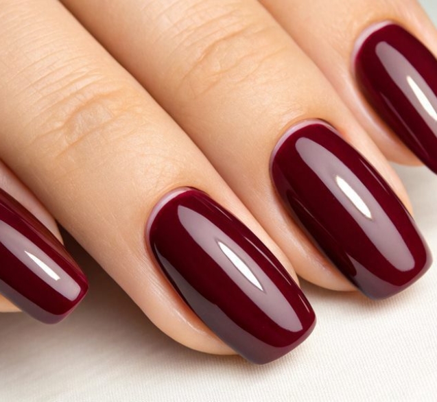 Close-up of burgundy manicured nails.